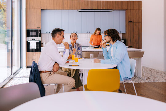 Colleagues Eating Lunch and Talking in Modern Office Kitchen During Casual Work Break