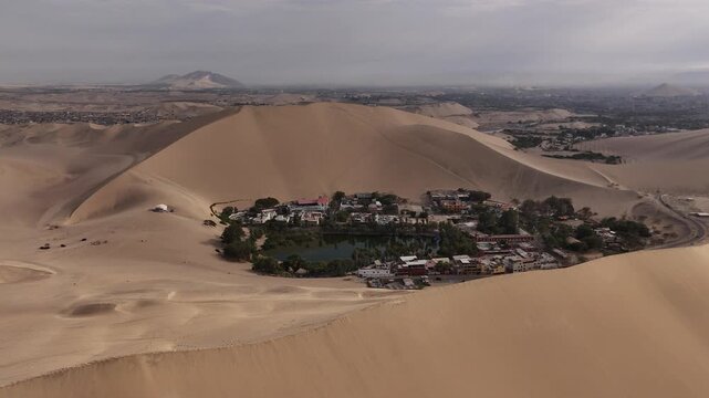 Aerial view of Huacachina oasis surrounded by giant dunes Peru