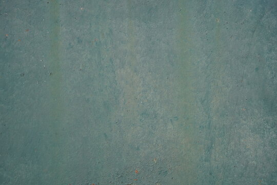 Dark teal green painted metal background with subtle weathered texture closeup. Aged iron surface with faint rust spots and flaking paint, rustic industrial backdrop.