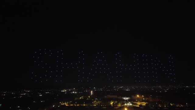 Aerial drone view of a spectacular drone light show spelling the word Syria at night. Illuminated drones forming glowing letters in the dark sky. Aerial entertainment celebrating Syrian heritage. Nigh