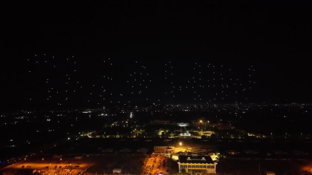 Aerial drone view of a spectacular drone light show spelling the word Syria at night. Illuminated drones forming glowing letters in the dark sky. Aerial entertainment celebrating Syrian heritage. Nigh