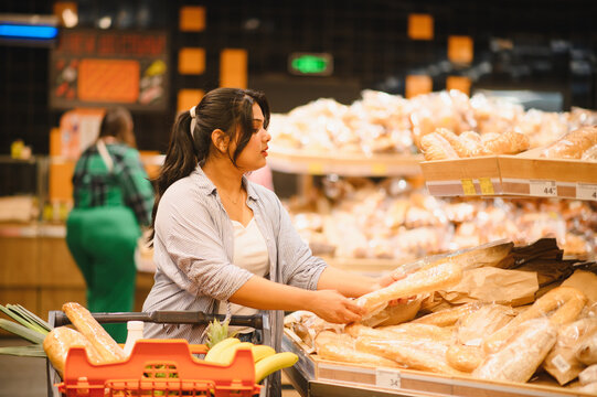 Indian woman shopping for fresh bread in supermarket