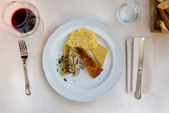 Friulian frico with potatoes and crispy frico served with yellow polenta and porcini mushrooms on plate