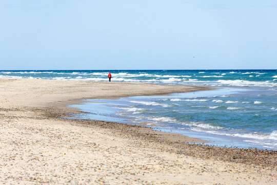 Lone walker on a quiet sandy beach in Grenen, Denmark