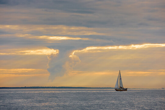 Yachtsmen are sitting amicably on board the boat at incredible sunset, sailing boat is in sailing regatta in the Gulf of Finland, magic splashing water, teamwork, Russia, St.Petersburg