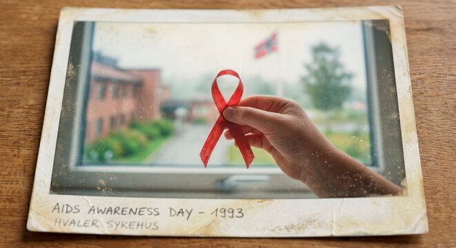 Hand holding red awareness ribbon in vintage instant photograph for World AIDS Day HIV education remembrance and prevention [copy space]