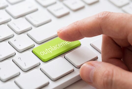 Finger Pressing Outplacement Button on Computer Keyboard for Career Transition Services