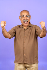 Fototapeta premium Senior man celebrating success with fists raised