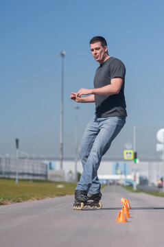 A Caucasian man rollerblades around the slalom course.