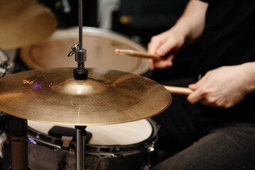 Obraz premium drummer plays drumset at rock concert with wooden drum sticks, close-up view of hands
