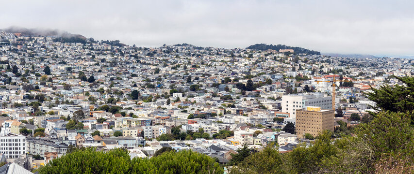 sf panorama-A sweeping panoramic view captures the dense residential neighborhoods and rolling hills of San Francisco under an overcast sky.