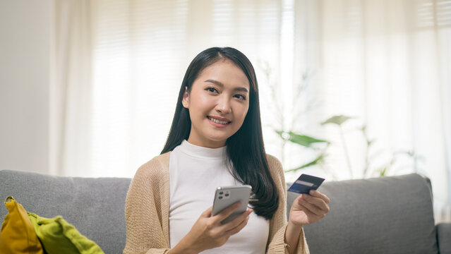Young Asian Woman Using Smartphone and Credit Card for Online Shopping and Digital Payment