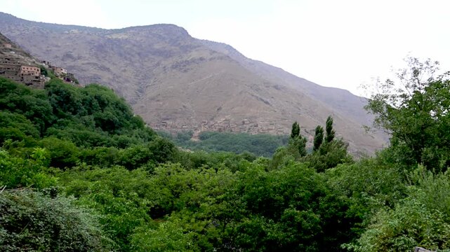 Marrakech, morocco. August 9, 2026. Beautiful panoramic view revealing a traditional berber village nestled in the arid atlas mountains, surrounded by a lush green oasis