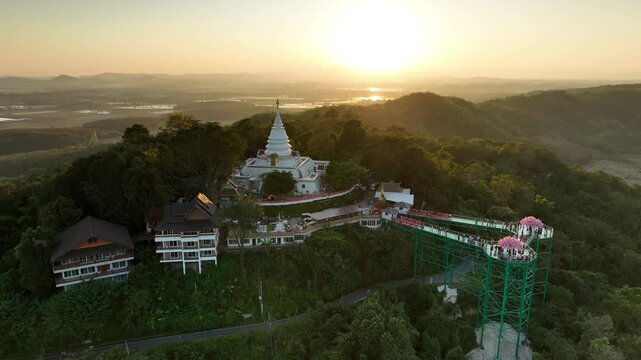 Phra Borommathat Phutthanimit Chedi and skywalk at sunset. Warm evening light creates a scenic setting for visitors in year 2023