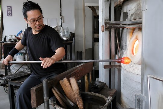 ガラス工房で吹きガラスを成形する職人