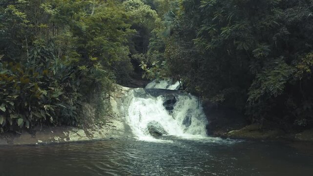 Beautiful waterfall flowing over rocks in a lush green tropical forest landscape.