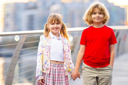 Portrait of children walking. Portrait with kids friendship. Outdoor portrait on city walkway. Kids portrait with holding hands.