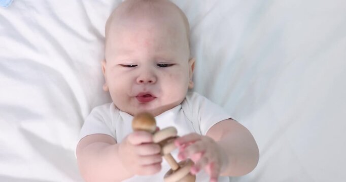 Cute little baby with teether on bed at home, top view. Camera moving in