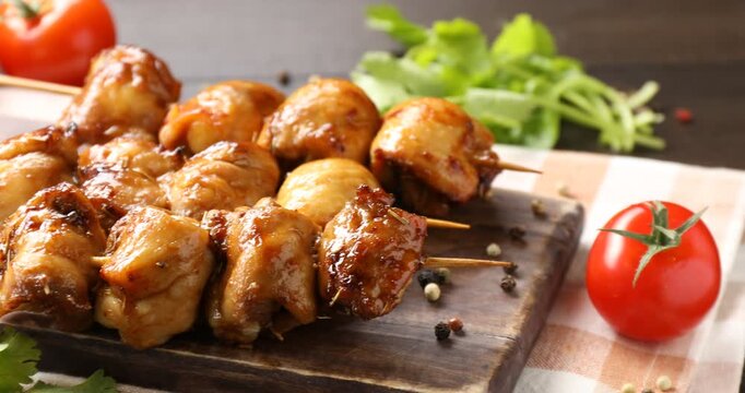 Delicious shish kebabs with spices and tomatoes on wooden table, closeup. Camera moving right