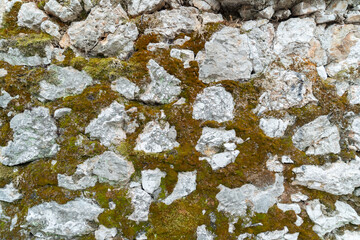 ​Horizontal close up photo of rough natural limestone rocks and boulders covered with green and brown moss for organic geological stone surface texture background © Marco