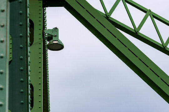 Gaspesie, Quebec, 06 June 2026 : A green metal bridge structure with rivets and a mounted spotlight against a light sky.