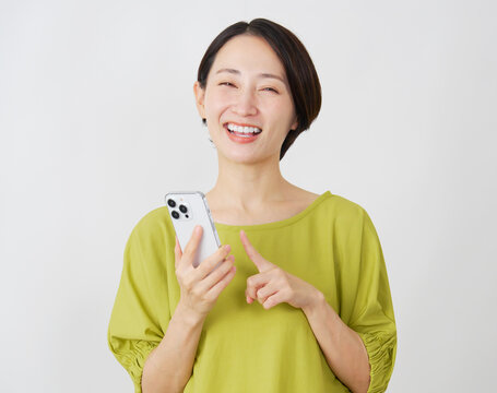 スマホを持つミドル女性　白背景　ポートレート　カメラ目線