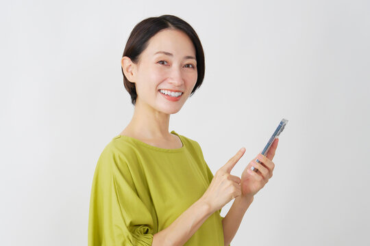 スマホを持つミドル女性　白背景　ポートレート　カメラ目線