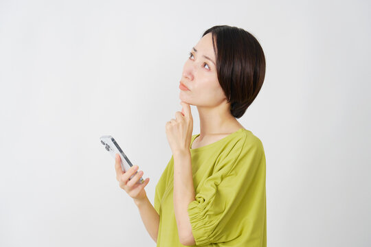スマホを持って考えるミドル女性　白背景