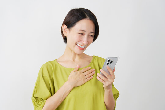 スマホを持って安心するミドル女性　白背景