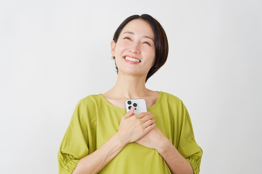 スマホを持って安心するミドル女性　白背景