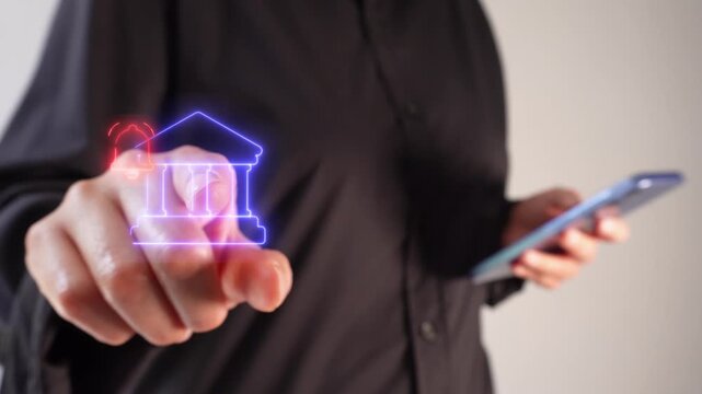 Bank notifications. A businesswoman holding a smartphone while pointing at a virtual bank icon featuring a notification bell.