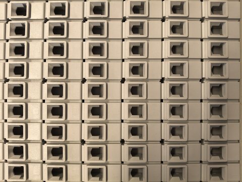 Grid pattern of beige plastic modular connector ports forming a minimalist industrial background.