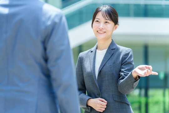 オフィスビルの前で立ち話をするビジネスパーソン