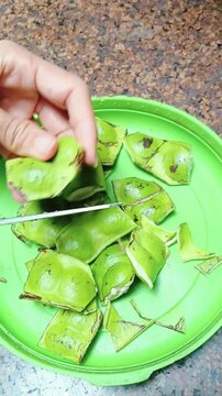 Cutting Petai Stink Beans with Scissors for Food Preparation