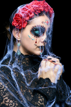 Halloween beauty portrait of woman. Female with Santa Muerte makeup and entangled in old web praying