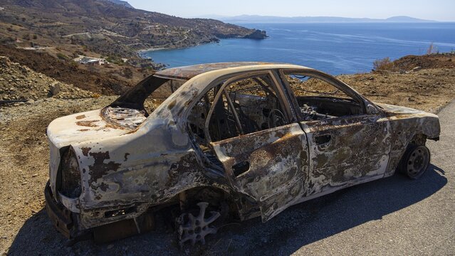 A rusty, burnt car with a view of the blue sea and rocky hills, forest fire, fire damage, fire on July 29 and 30, 2026, Agios Pavlos, south coast, Retimnon province, Crete, Greek Islands, Greece