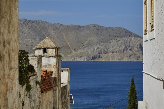 Tranquil sea view framed by old buildings and rocky mountains in the background, Symi Town, Symi, Dodecanese, Greek Islands, Greece