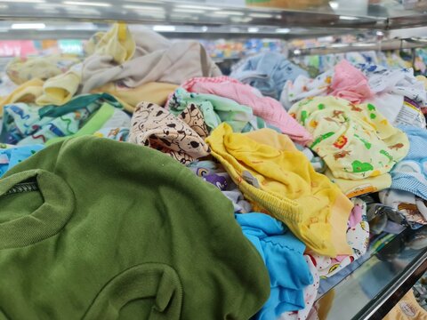 Close-up of a messy pile of bright and colorful patterned baby clothes on a retail store display shelf