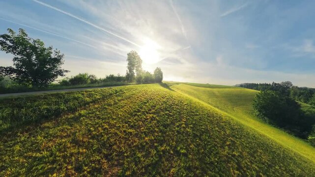 Morning drone footage slowly rising above a rural road and lush green meadows in the M&uuml;hlviertel. Warm sunlight, forests and patches of low clouds create a scenic Upper Austrian landscape.