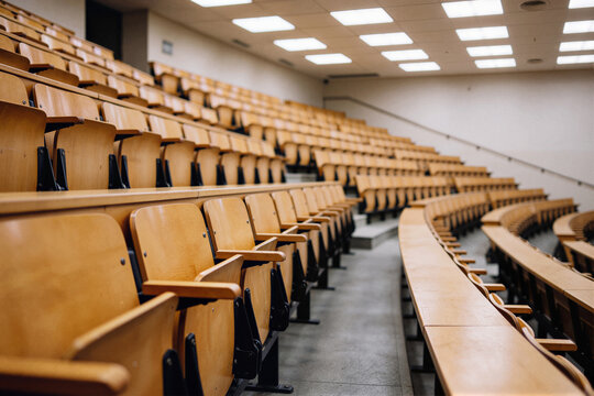 Empty tiered lecture hall with light wooden seats in amphitheater layout