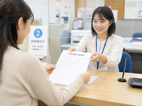市役所の証明書交付窓口で戸籍関係書類を受け取る女性のイメージ