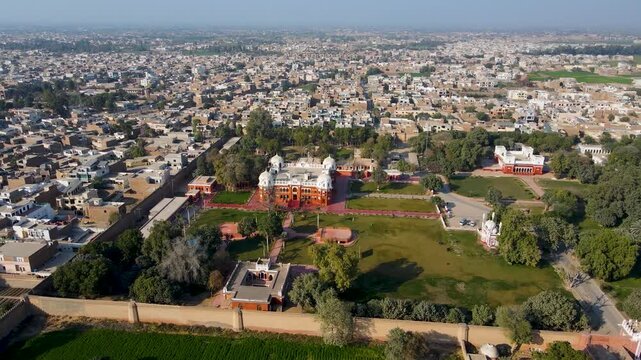Aerial view of the Darbar mahal bahawalpur surrounded by green trees and grass with a city in the background, Bahawalpur, Punjab, Pakistan.