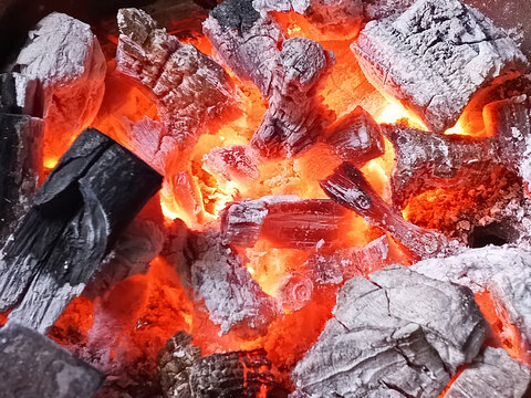 close up of burning wood charcoal with glowing red hot embers for grilling, energy, bbq and cooking, fire texture background
