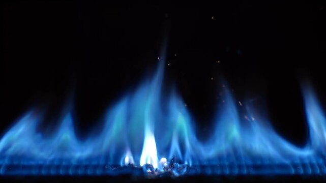 Blue gas flames burning on a kitchen stove burner with sparks