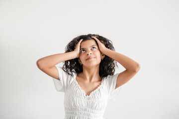 Naklejka premium Teenage girl laughing with hands in hair, looking up, horizontal portrait