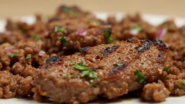 Macro close-up of delicious browned ground meat seasoned with fresh herbs and chopped red onions, savory cooked minced beef or lamb dish detail.