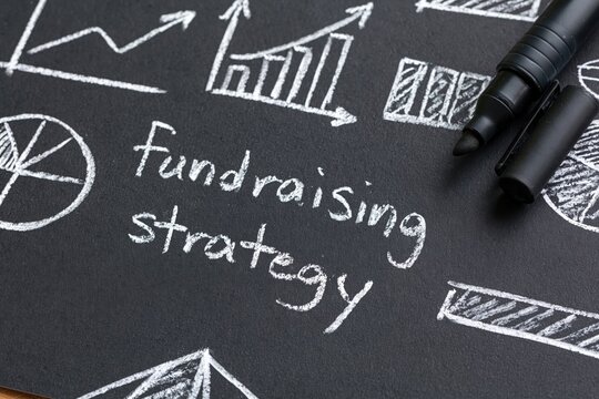 Fundraising strategy written in chalk with business finance charts graphs planning growth capital nonprofit data