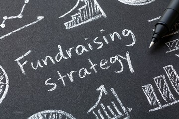 Fototapeta premium Fundraising strategy written on a chalkboard with business finance planning growth development capital investment