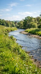 Fototapeta premium Serene River Winding Through Lush Green Countryside Under a Blue Sky.
