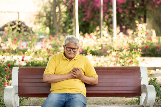 Heart attack concept. Indian Senior man suffering from chest pain outdoor in park.